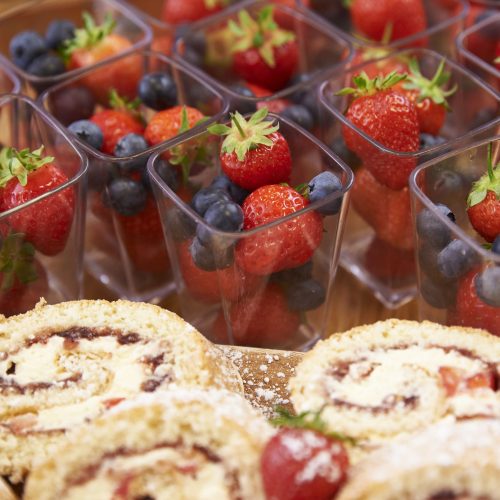 boxes of strawberries and blueberries as well as slices of cake