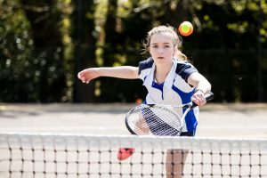 Girl hitting tennis ball
