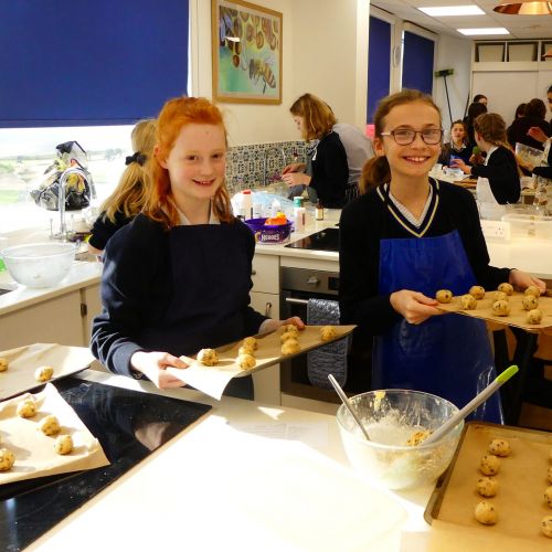 students with their rolled cookies on a tray