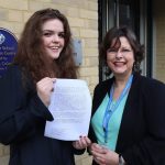 student smiling holding an exam paper