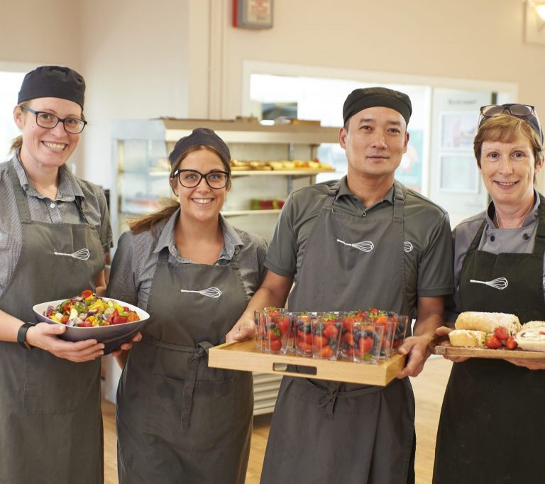 Cooks holding cake, fruits and salad