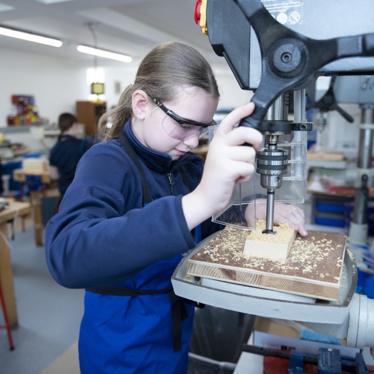 Students using a drill to file down wood